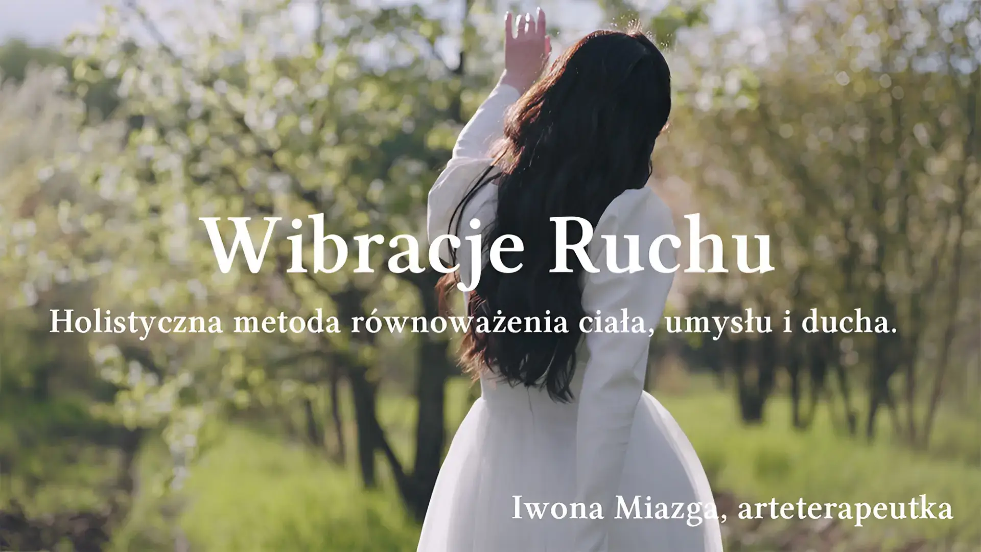 Taniec intuicyjny na łonie natury – kobieta w białej sukni z uniesioną ręką wśród kwitnących drzew.