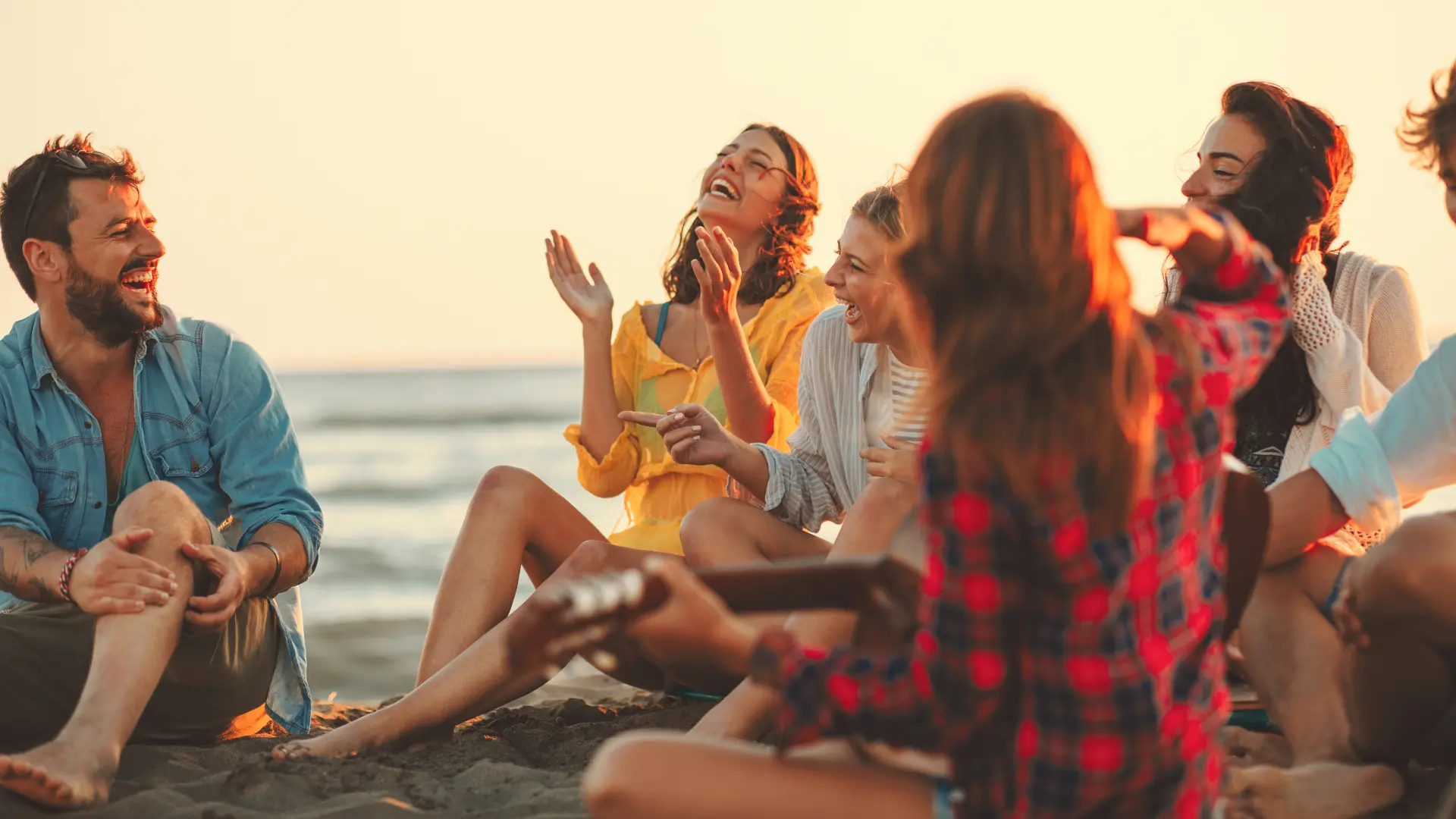 Grupa młodych osób śmiejących się przy zachodzie słońca – wyjazdowe warsztaty rozwojowe w Polsce, integracja i relaks.